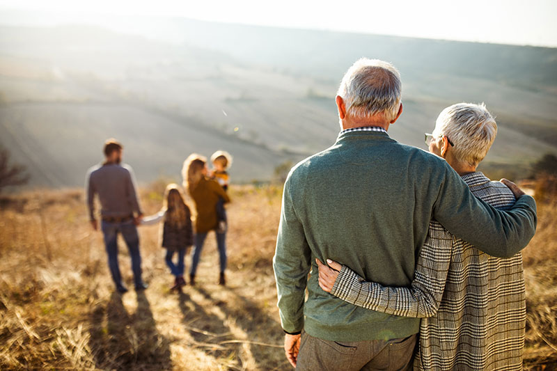 elderly couple looking fondly upon their child's family