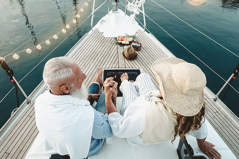 elderly couple holding hands on the front of a boat